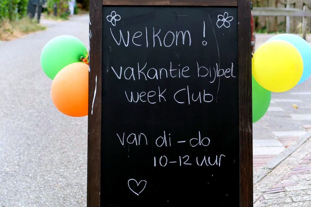 Krijtbord met welkomsttekst en ballonnen bij de ingang